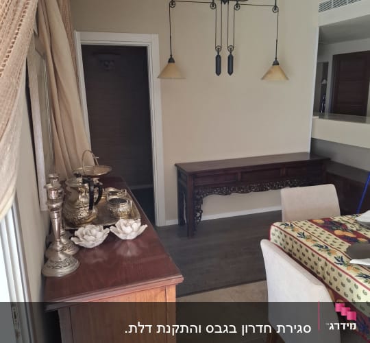 קיר גבס עם מנורה תלויה ושולחן עץ